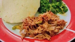 A plate with a mound of white food, possibly a type of bread or dumpling, alongside a serving of green leafy vegetables and a portion of shredded meat. - SANAWARI LODGE (Arusha)