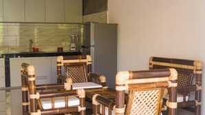 A kitchen with a modern design, featuring a marble backsplash and a built-in refrigerator. There are two wooden chairs with woven backs and a small table. - The Raka Villa Amed (Karangasem)