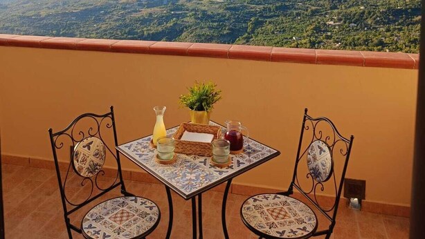 A balcony with a table and chairs, overlooking a mountainous landscape. - Polizzihouse - Holiday House with Panoramic Terrace, in the Heart of the Madonie Mountains. (Polizzi Generosa)