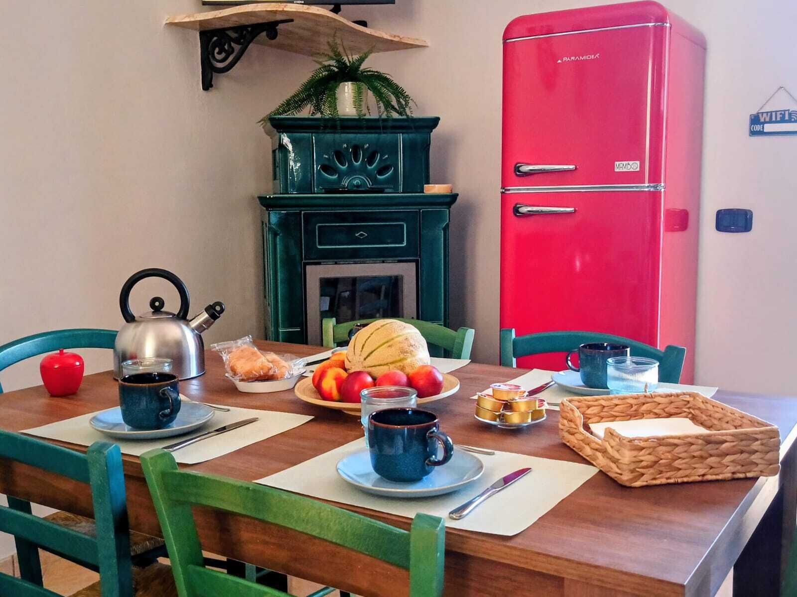 A dining table set with a kettle, teapot, plates, cups, and food items.