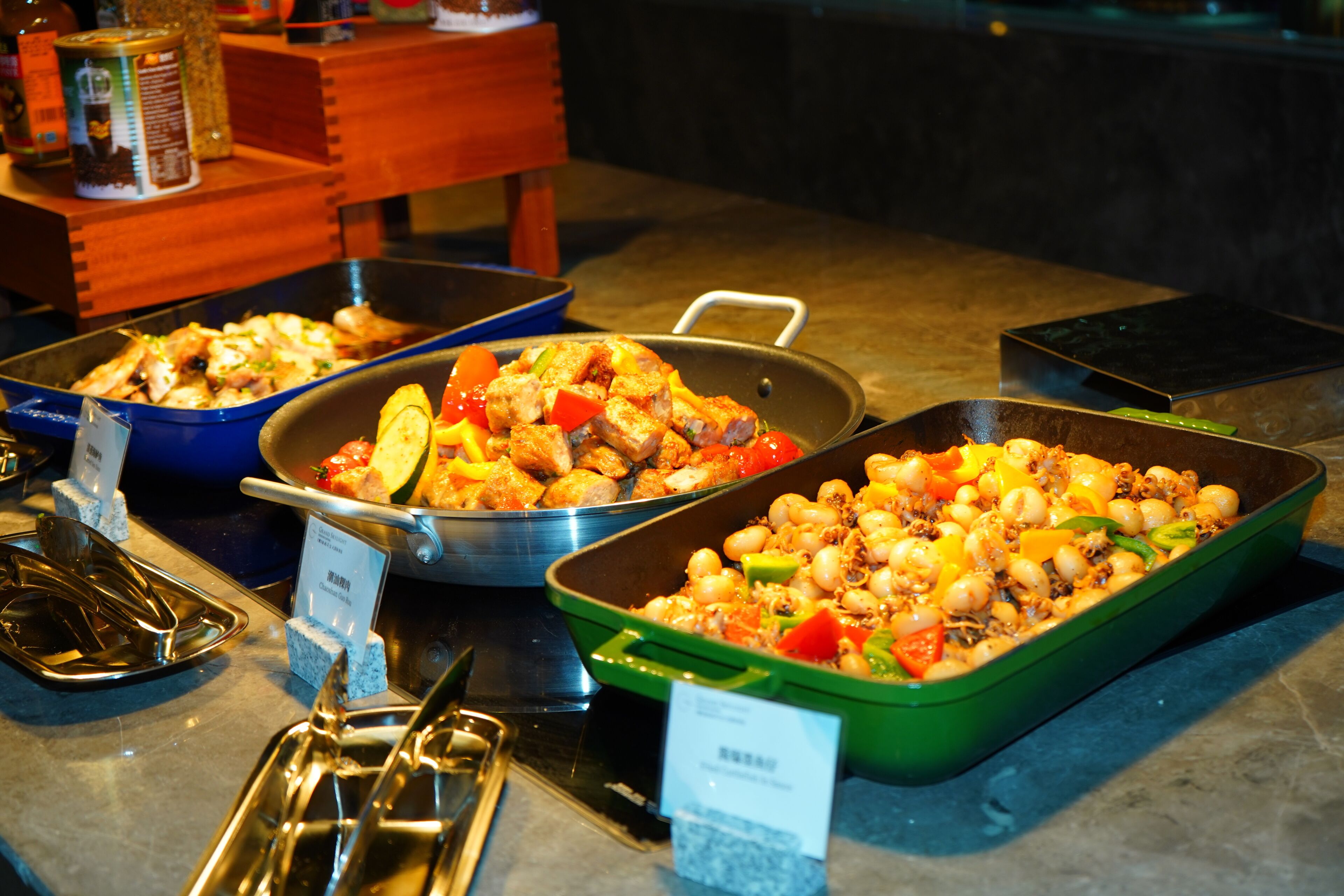 Een buffet met diverse gerechten, waaronder kip, groenten en mogelijk zeevruchten.