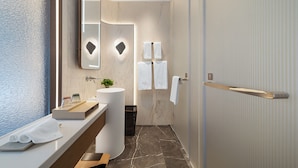Un baño moderno con tocador de mármol, un espejo grande y un perchero.