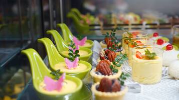 A variety of desserts displayed in green ceramic cups and glasses, some with decorative elements like berries and leaves.