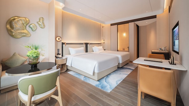 Una habitación de hotel moderna con una cama grande, un escritorio y una zona de estar.