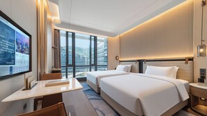 Habitación de hotel con una cama grande, un escritorio y un televisor.