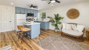 Una cocina moderna con gabinetes azules, una isla central y dos ventiladores de techo.