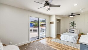 Un dormitorio con cama, ventilador de techo, vistas por una puerta corrediza y un balcón pequeño.