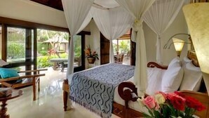 Un dormitorio con cama, mesita de noche, lámpara y vistas al exterior.