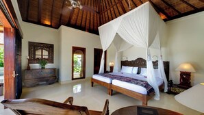 Un dormitorio amplio con una cama grande, un ventilador de techo y un techo de madera.