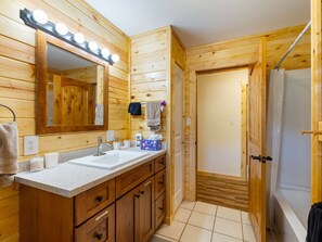 Un bagno in stile baita con lavabo doppio, mobile contenitore e specchio illuminato.