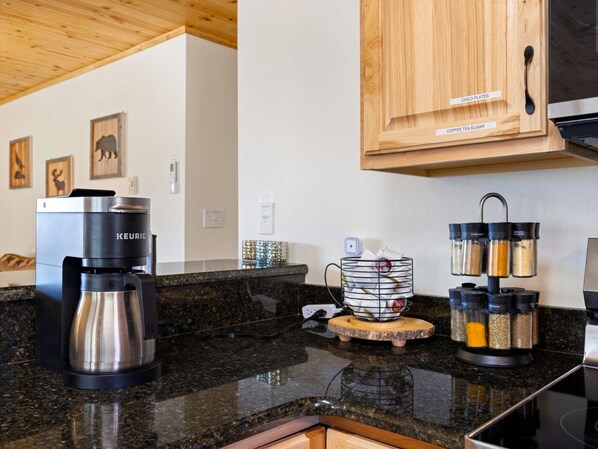Una cocina con una cafetera Keurig, un molinillo de café y recipientes para especias.