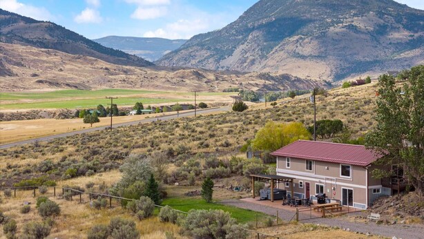 A two-story building with a red roof, a covered patio, and a view of a mountainous landscape.
