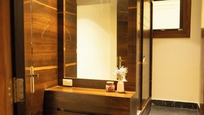 A modern bathroom with a large mirror, wooden vanity, and a small vase with flowers. - Cilantro Unwind Delisso Abode Pelling (Gyalshing)