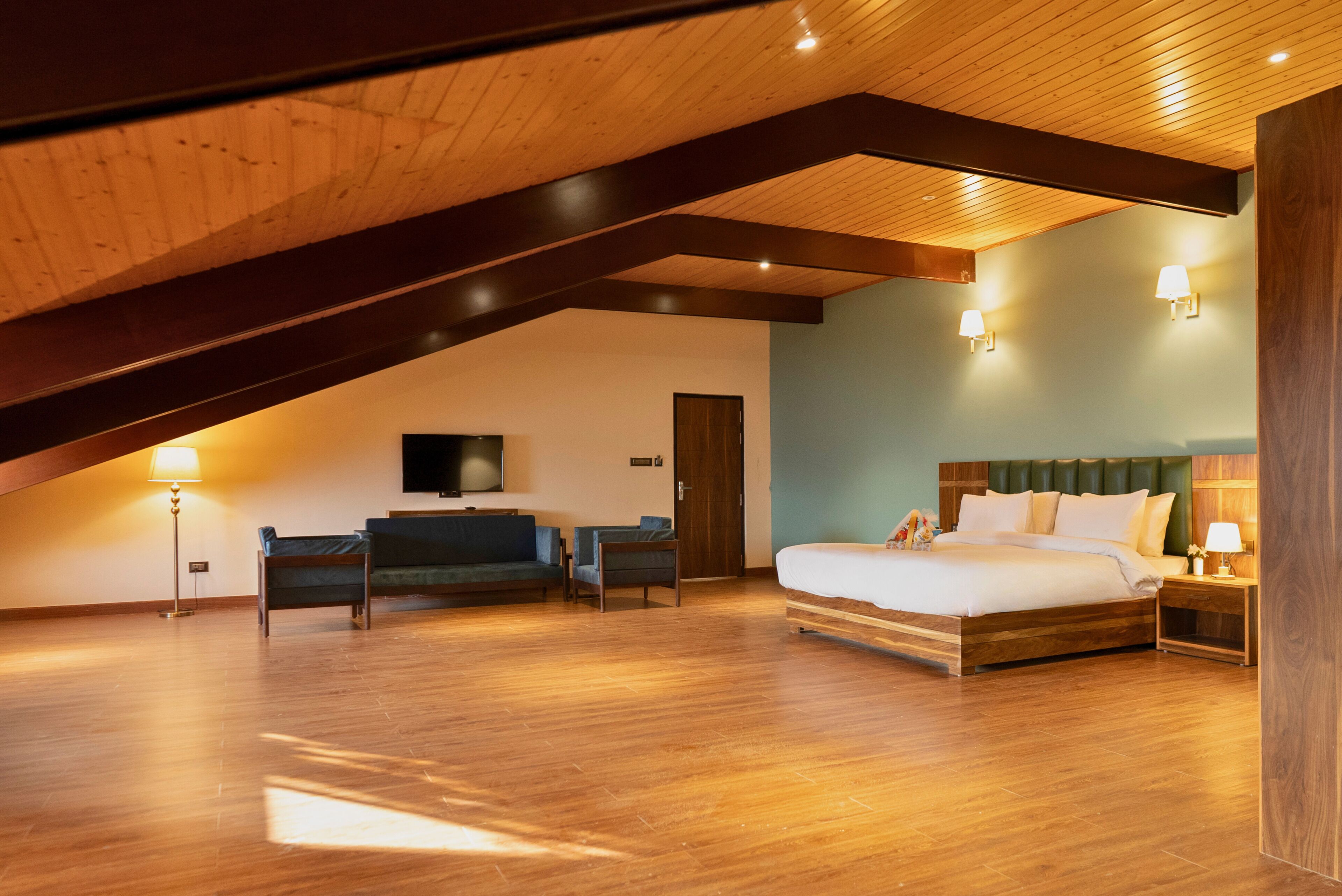 A bedroom with a wooden ceiling, a bed, a TV, and two chairs.