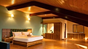 A spacious bedroom with a large bed, wooden ceiling beams, and a built-in wardrobe. - Cilantro Unwind Delisso Abode Pelling (Gyalshing)