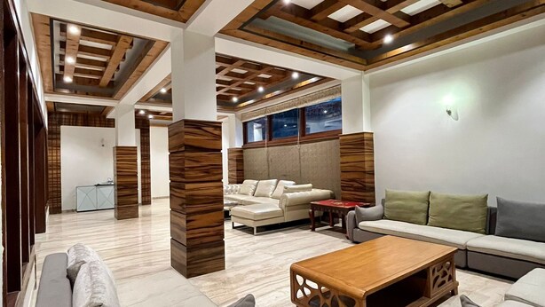 A spacious living area with a high ceiling, wooden beams, and a modern sofa set. - Cilantro Unwind Delisso Abode Pelling (Gyalshing)