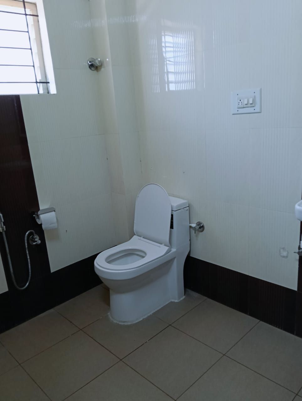 A small, clean bathroom with a toilet, a shower, and a window.