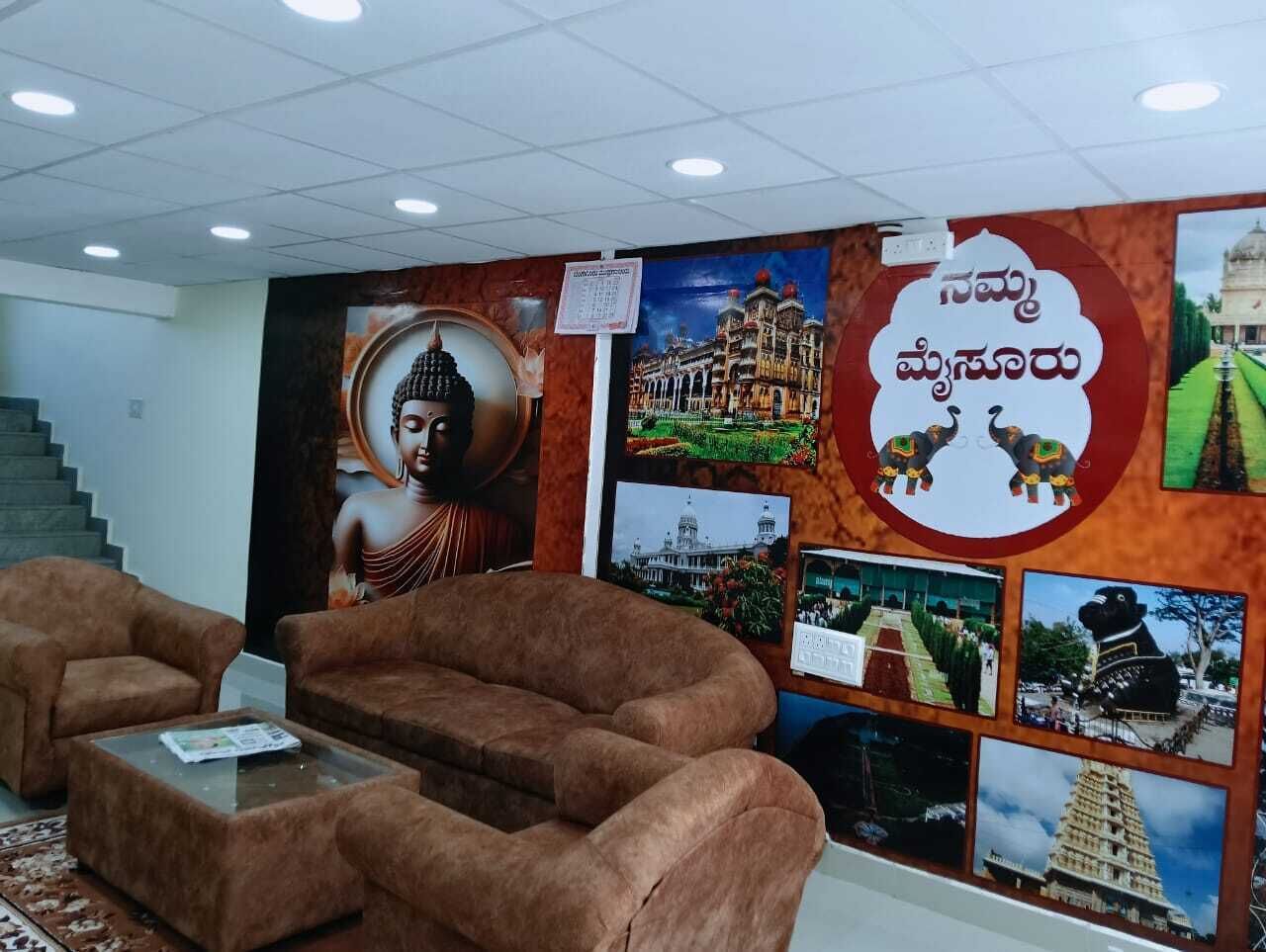 A lobby with brown sofas, a glass coffee table, and a wall decorated with cultural and historical images.