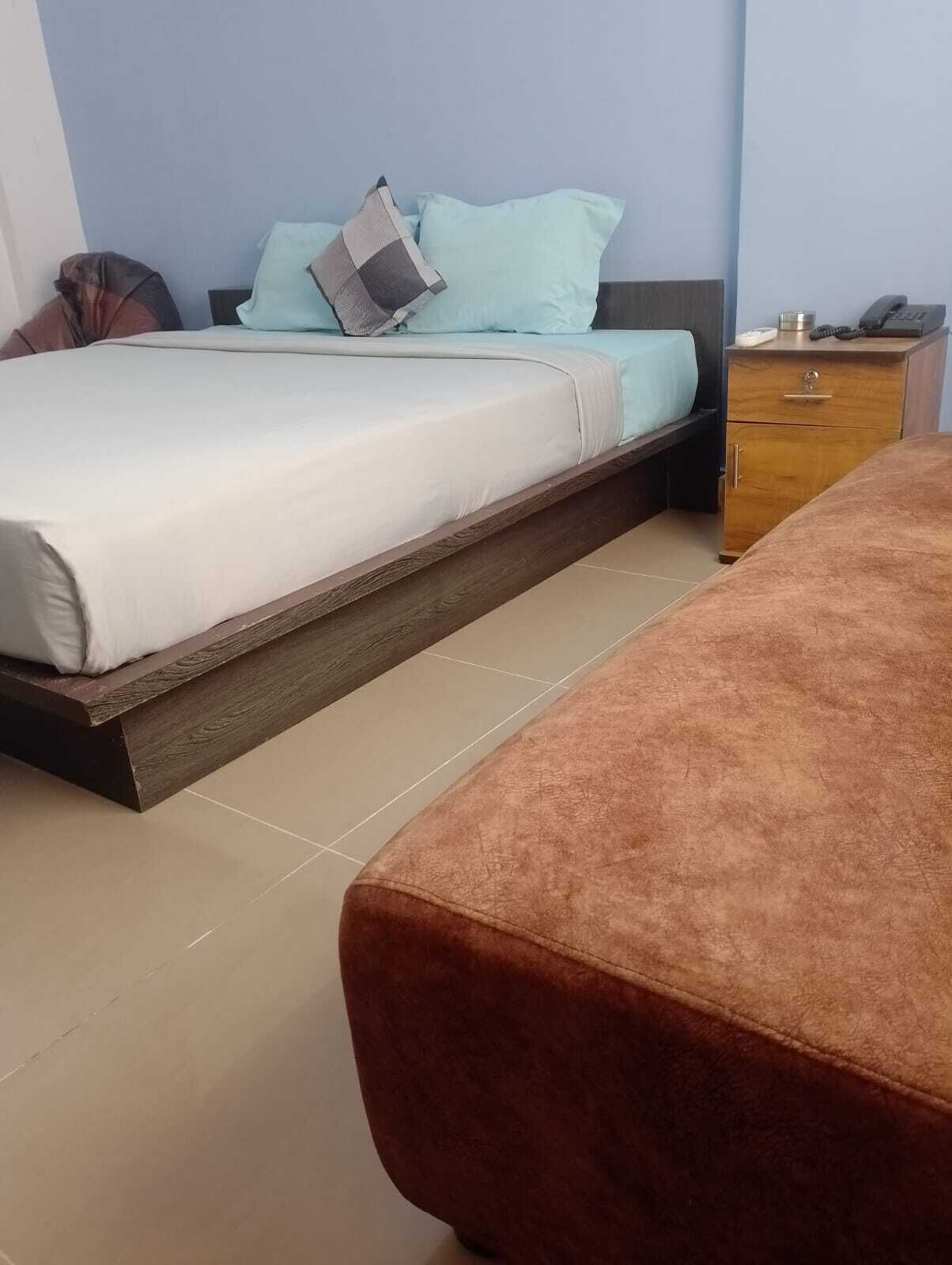 A bedroom with a bed, a bedside table, a nightstand, and a wooden bench.