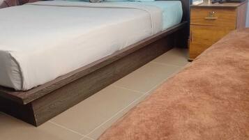 Una camera da letto con un letto, un comodino, una panca di legno e una tavola laterale.