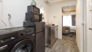 A compact hotel room with a washing machine, a compact kitchenette, a bed, and a bathroom. - F・CROSS・EBISU (Osaka)