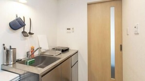 A compact kitchen with a sink, utensils, and a door. - F・CROSS・EBISU (Osaka)