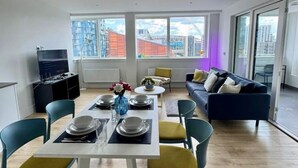 A modern living room with a dining area, large windows, and a city view. - Modern 3 Bed Wembley Stadium View Apartment (Wembley)