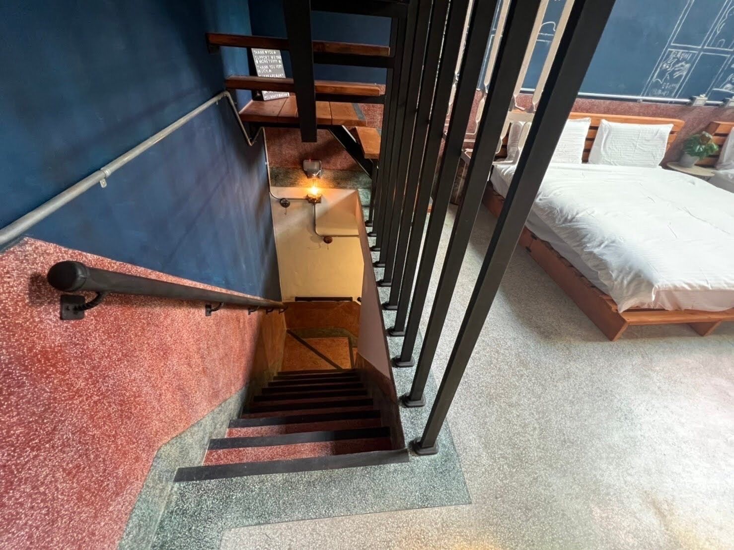 A staircase with a handrail, a wooden bench, and a bed with white bedding.