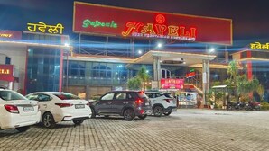 A hotel named Haveli with a signboard, parked cars, and a well-lit entrance.