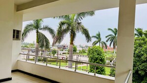 A balcony with a view of a green park and palm trees.