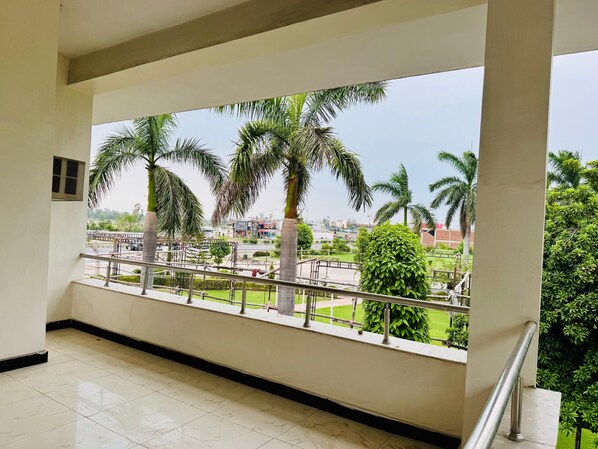 A balcony with a view of a green park and palm trees.