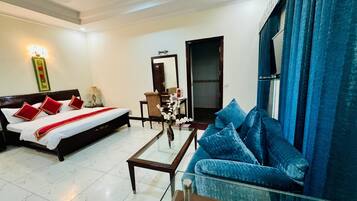 A hotel room with a bed, a sofa, a coffee table, and a mirror.