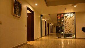 A well-lit hallway with a decorative panel, a framed artwork on the wall, and a door leading to another room.