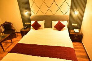 A hotel room with a large bed, two nightstands, a chair, and a small table.