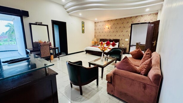A hotel room with a bed, a sofa, a coffee table, a TV, and a balcony.