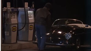 Un coche clásico en una gasolinera, con una persona repostando.