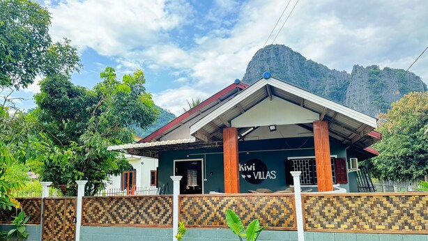 Un bâtiment à deux étages, sur lequel on peut lire l’inscription  « Kiwi Villas », avec une chaîne de montagnes en arrière-plan.
