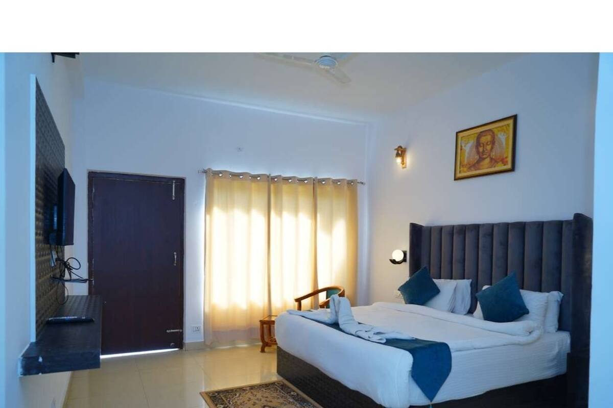 Une chambre à coucher avec un lit, une table de chevet, une chaise, une porte et une fenêtre avec des rideaux.