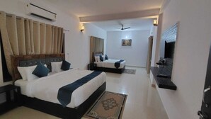 A hotel room with two beds, a large mirror, a ceiling fan, and a wall-mounted air conditioner. - Blue River Resort (Ramnagar)