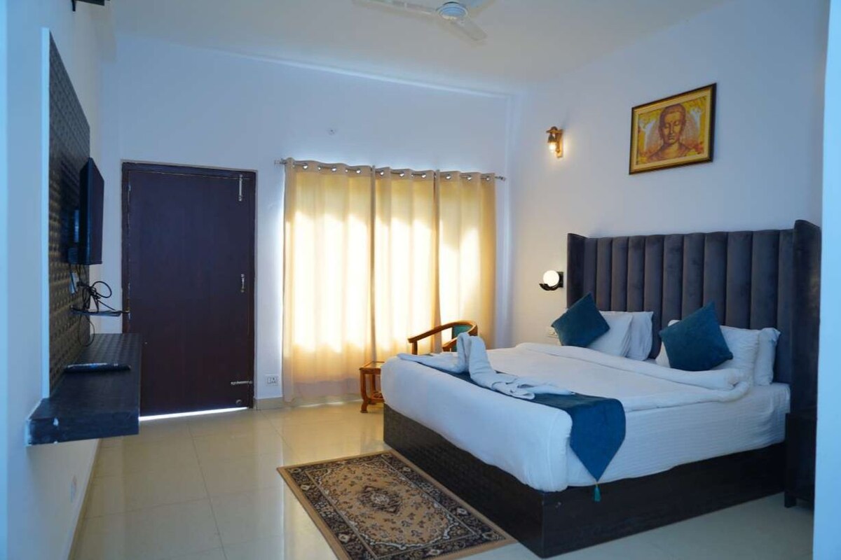A bedroom with a bed, a nightstand, a chair, a door, and a window with curtains.