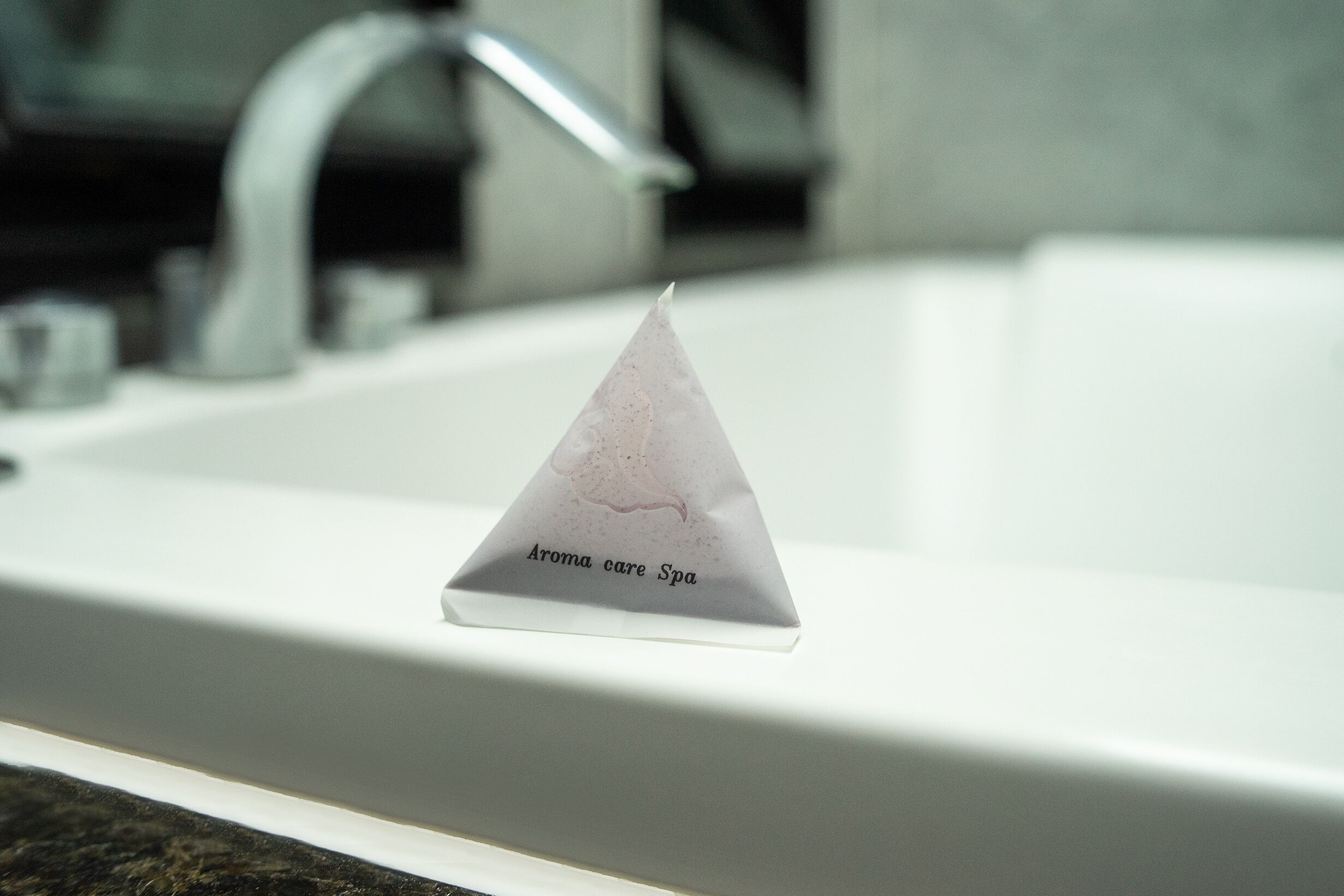 A white triangular object with text on a bathroom sink.