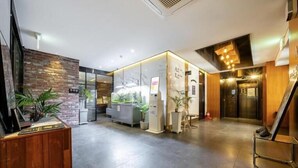 Un moderno vestíbulo de hotel con una recepción, un separador de vidrio y una pared de madera.