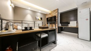 Una cocina moderna con suelo de mármol, horno empotrado, cafetera y televisor de pantalla plana.