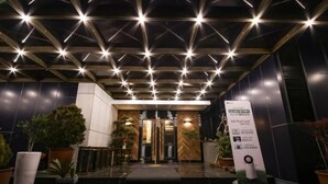 Entrada de hotel con diseño moderno, que presenta un patrón geométrico en el techo y plantas en macetas.
