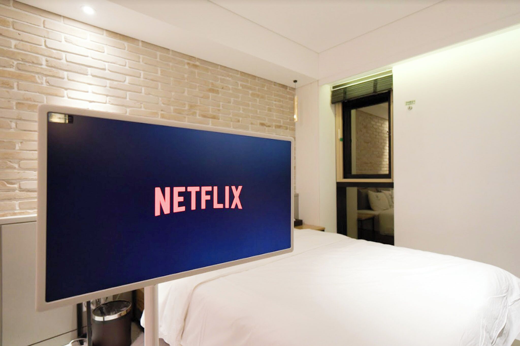 A hotel room with a large flat-screen TV mounted on the wall displaying the Netflix logo.