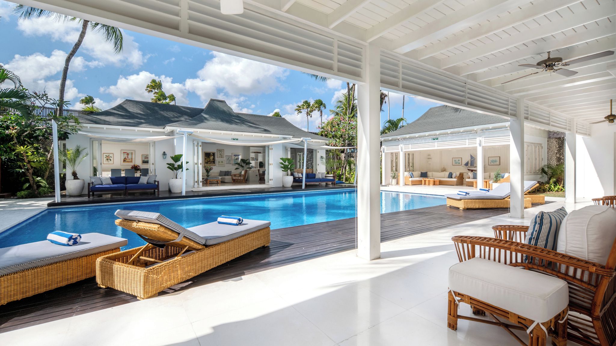 A poolside area with lounge chairs, a covered seating area, and a view of the surrounding landscape.