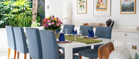 A dining area with a white table, blue chairs, and a floral centerpiece.