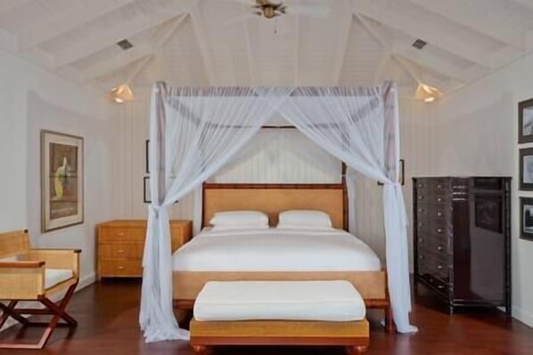 A bedroom with a canopy bed, wooden headboard, bedside tables, and a wardrobe.