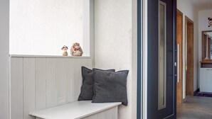 Eine Bank mit zwei Kissen, eine Tür und ein kleines Regal mit Figuren.