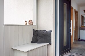 A bench with two pillows, a door, and a small shelf with figurines. - Apartment 'Im Fränkischen Seenland' with Private Terrace and Wi-Fi (Abenberg)